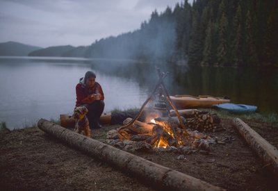 Eine Frau sitzt vor einem Lagerfeuer