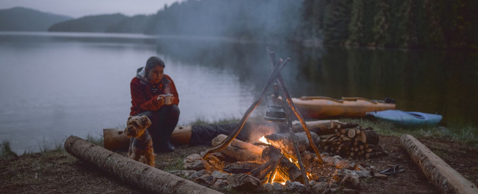 Eine Frau sitzt vor einem Lagerfeuer